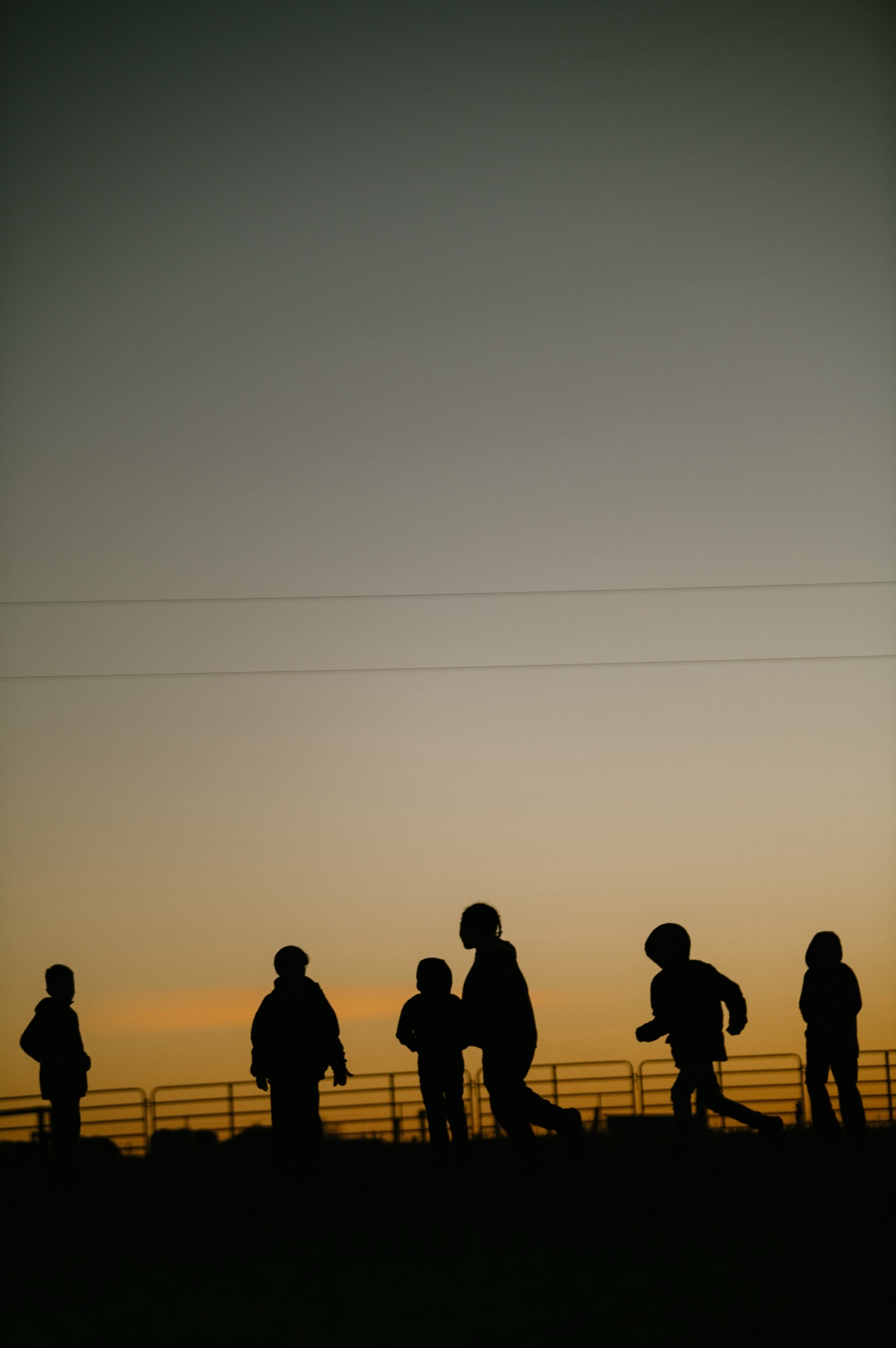 Children silhouetted against a burning sunset sky