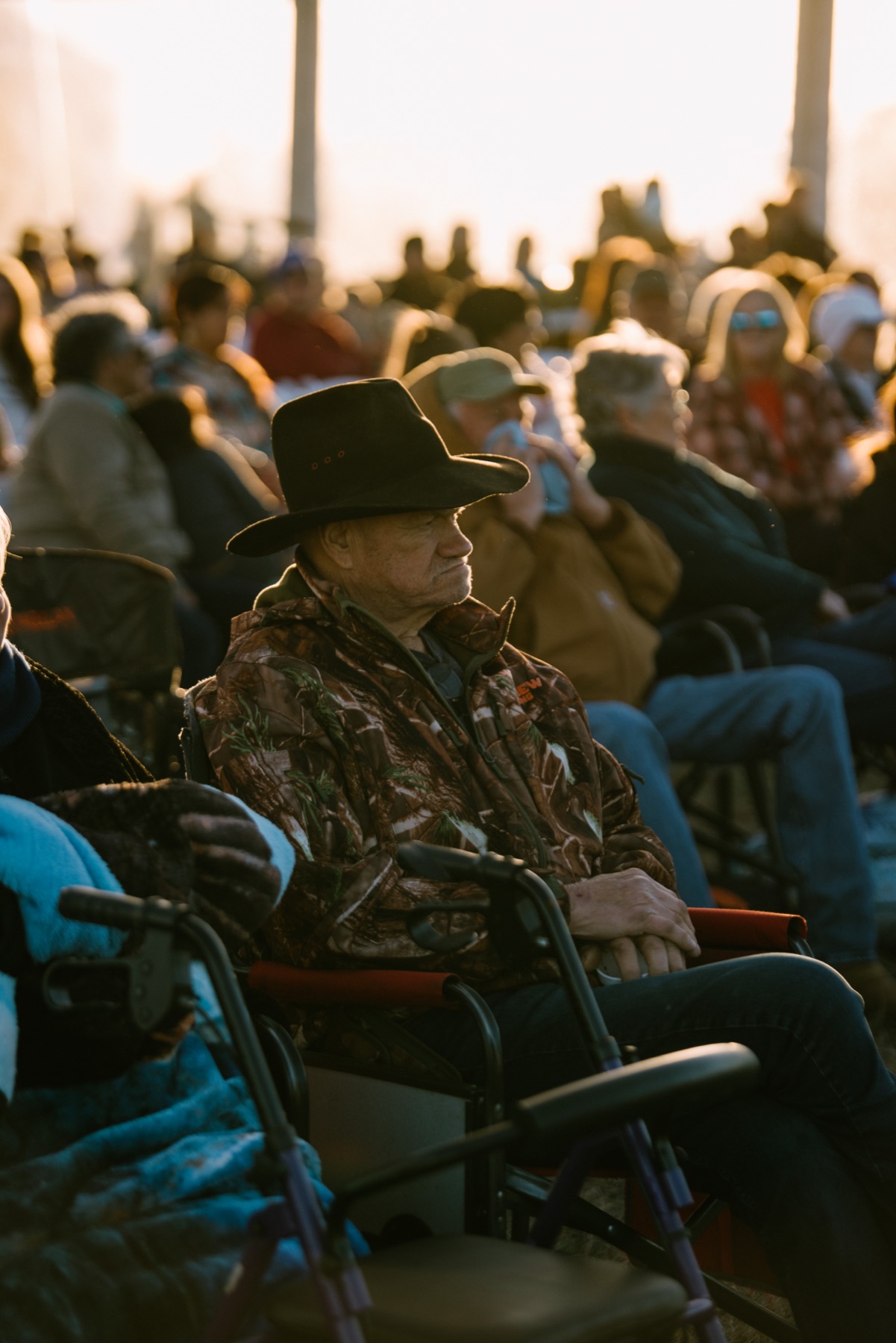 Older man in a cowboy hat in the crowd at golden hour