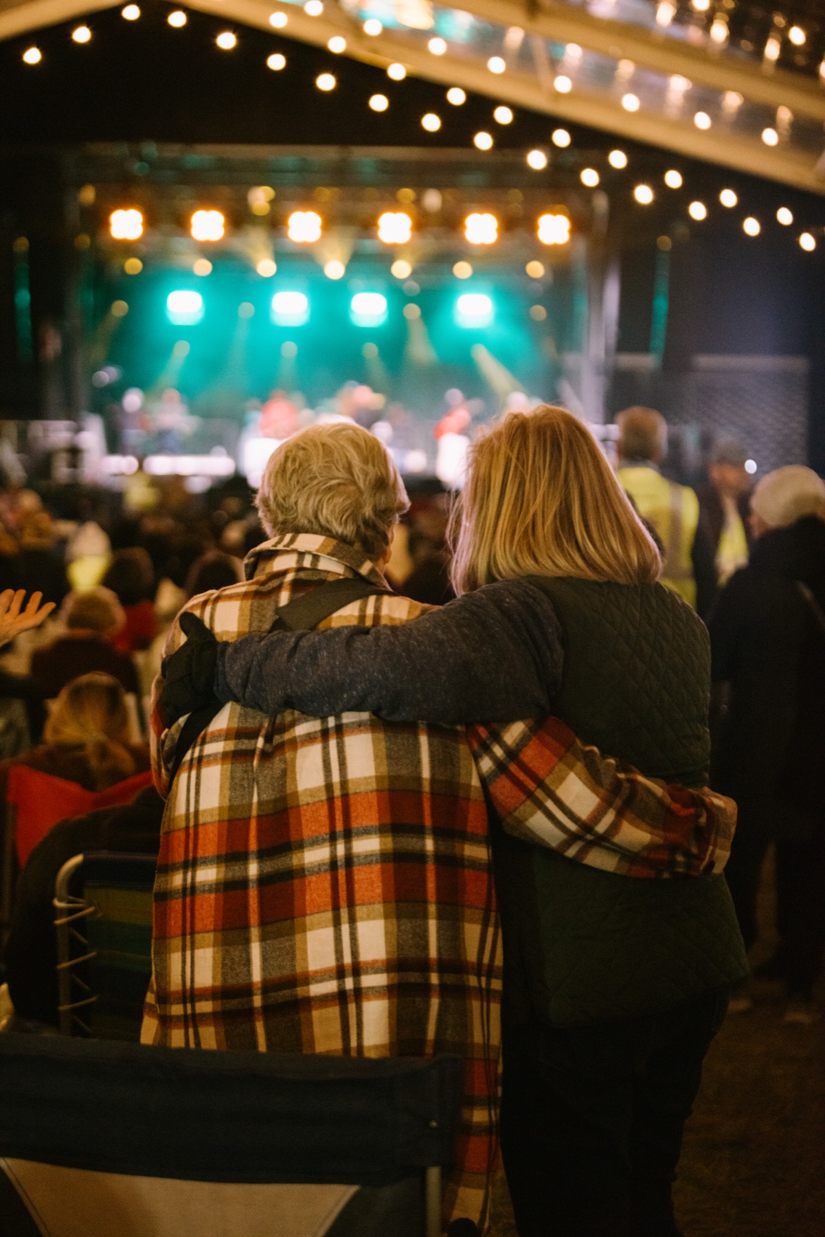 Two people embracing at night, watching the stage