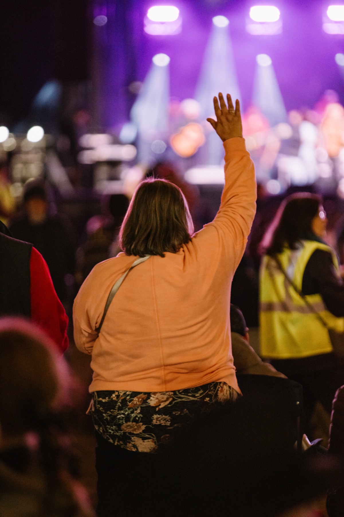 A worshipper with hand raised under stage lights